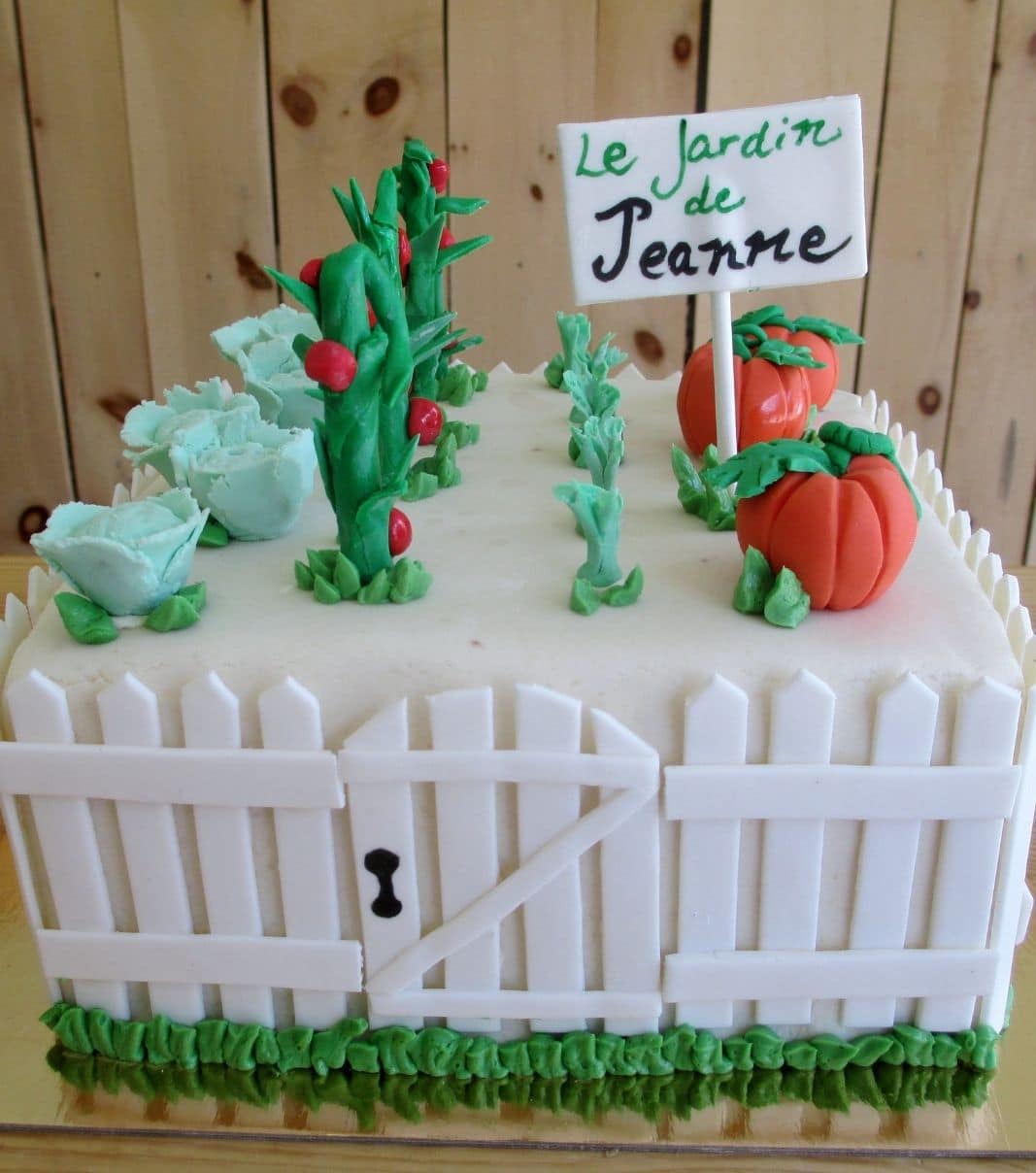 Gâteau d'anniversaire sur mesure de Jeanne: gâteau en forme de potager en 3D avec une couverture en pâte d'amande et décoré d'une clôture et de légumes de jardin (citrouilles, tomates, carottes, choux) en fondant.