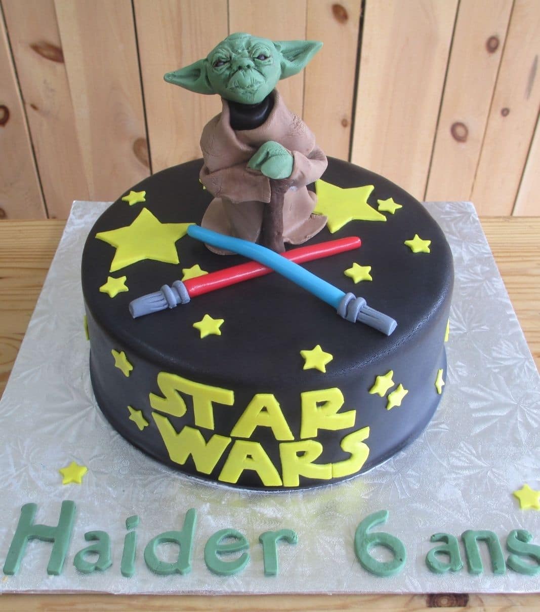 Gâteau d'anniversaire sur mesure des 6 ans de Haider: gâteau à thématique Star Wars avec une couverture en fondant noire et décoré d'étoiles, de sabres laser et d'une figurine de Yoda en fondant.