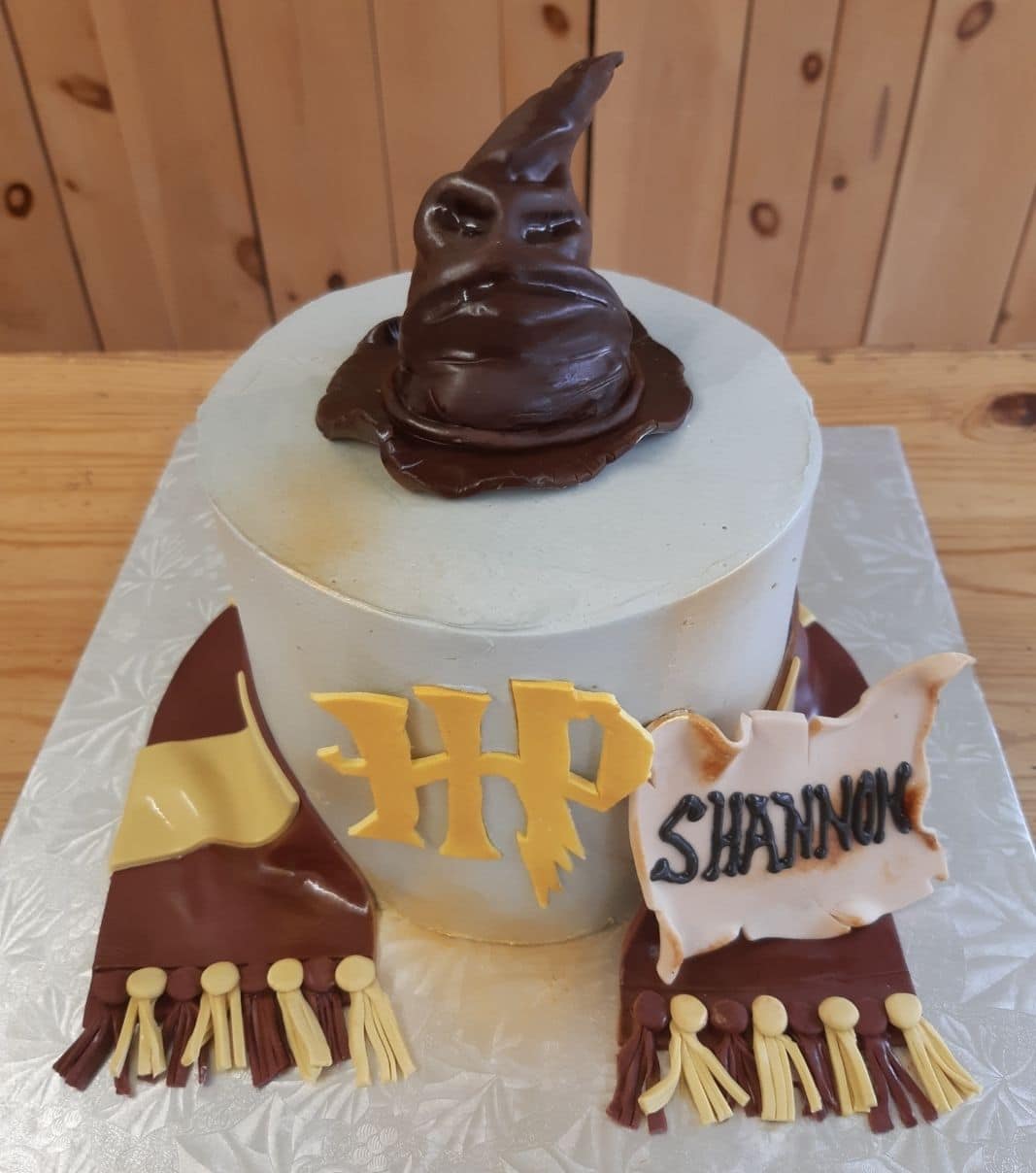 Gâteau d'anniversaire sur mesure de Shannon: gâteau à thématique Harry Potter avec une couverture en fondant et décoré d'un Choixpeau magique et d'une écharpe de Gryffondor en fondant.