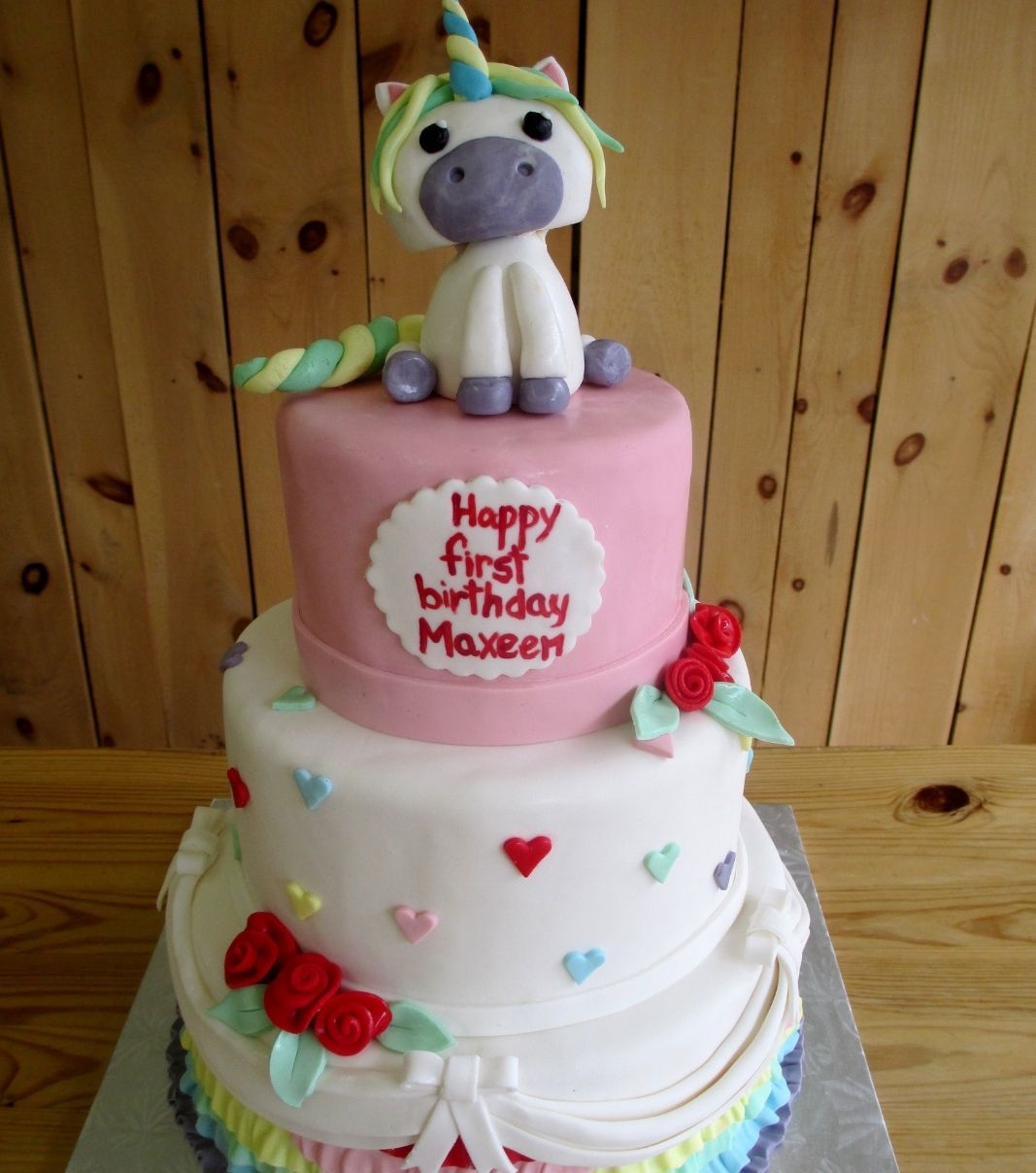 Gâteau d'anniversaire sur mesure du 1 an de Maxeen: gâteau de 3 étages à thématique de licorne avec une couverture en fondant et décoré d'une figurine de licorne, de fleurs et de drapés en fondant.