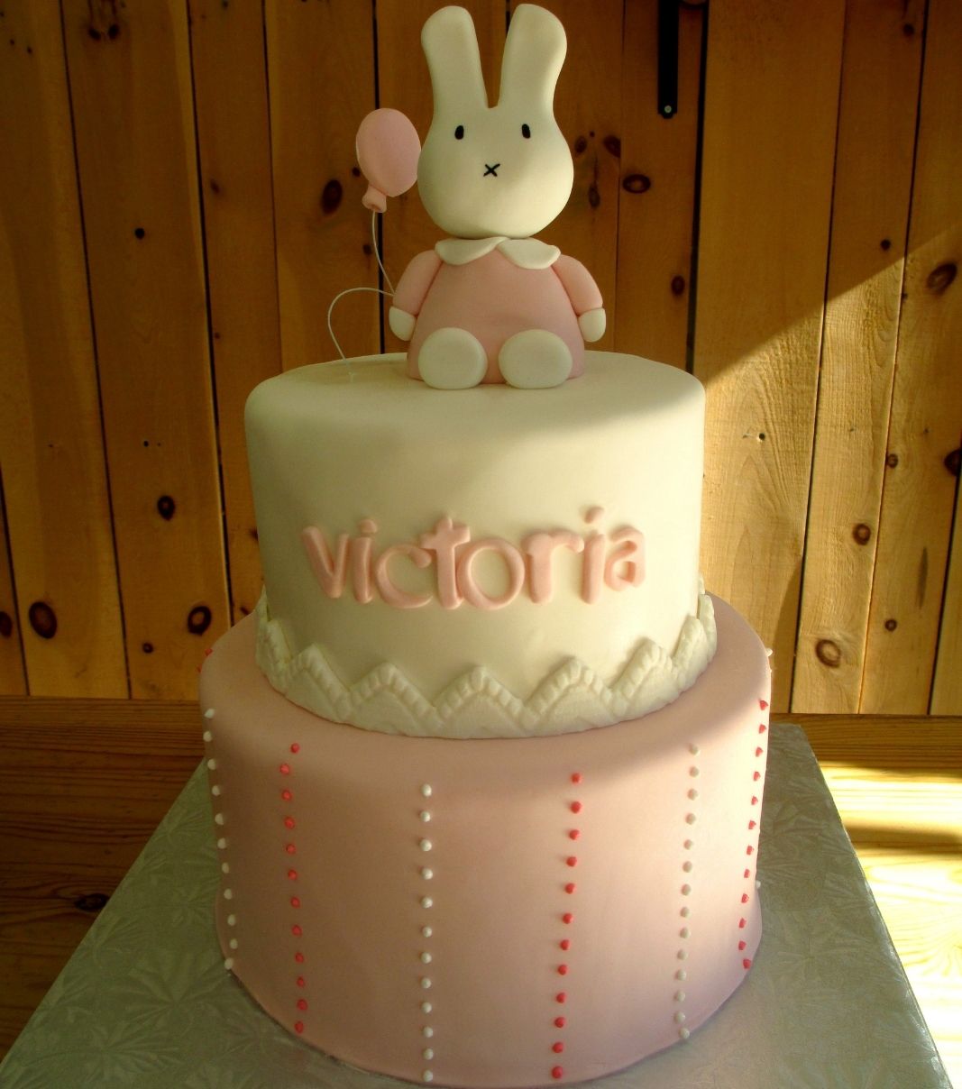 Gâteau shower de bébé fille de Victoria: gâteau rond de 2 étages avec une couverture au fondant et décoré d'une lapine 3D et d'une bordure en dentelle.