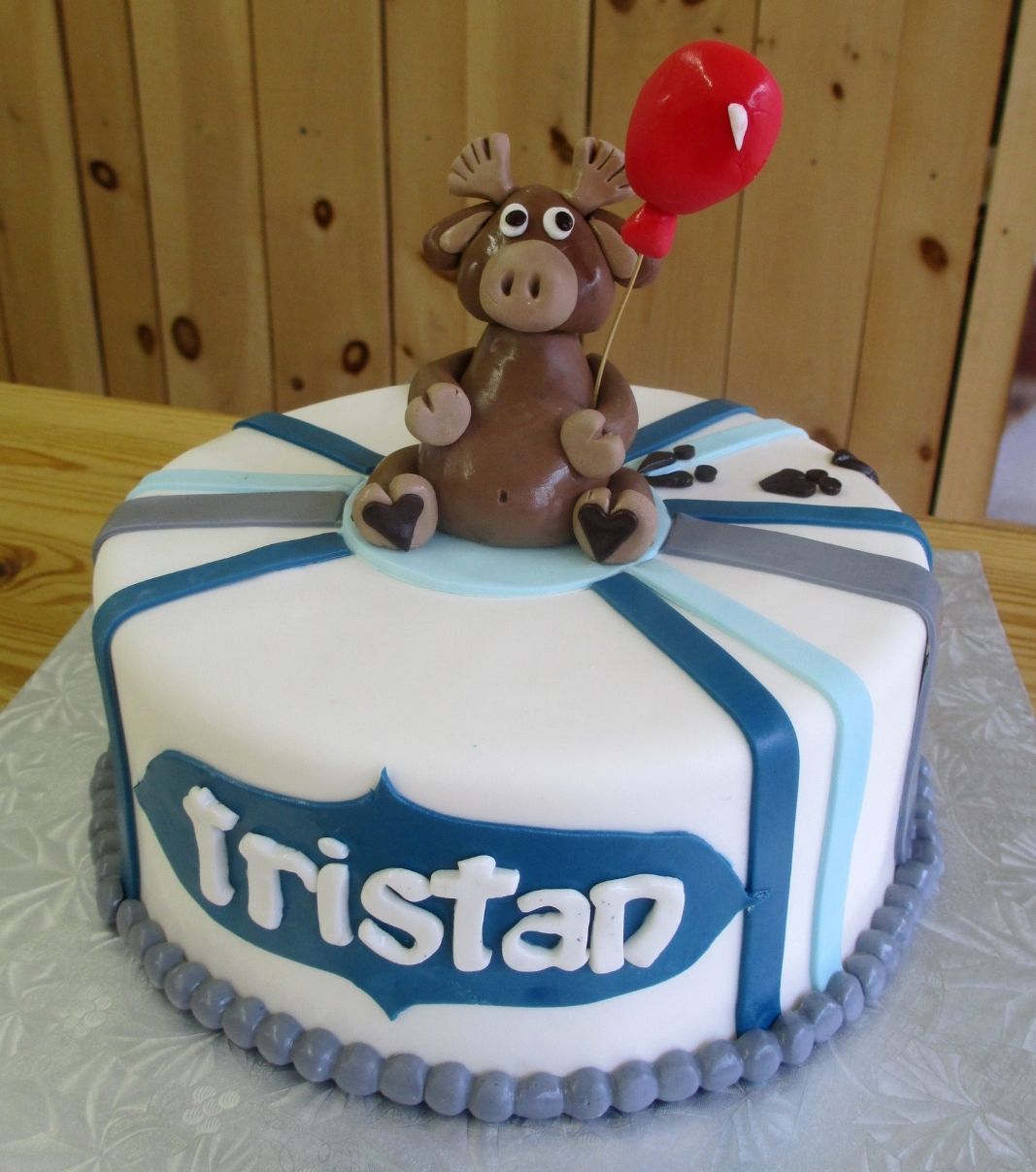 Gâteau shower de bébé garçon de Tristan: gâteau à thème bleu et bleu clair avec une couverture au fondant blanc et décoré d'un caribou et son ballon rouge.