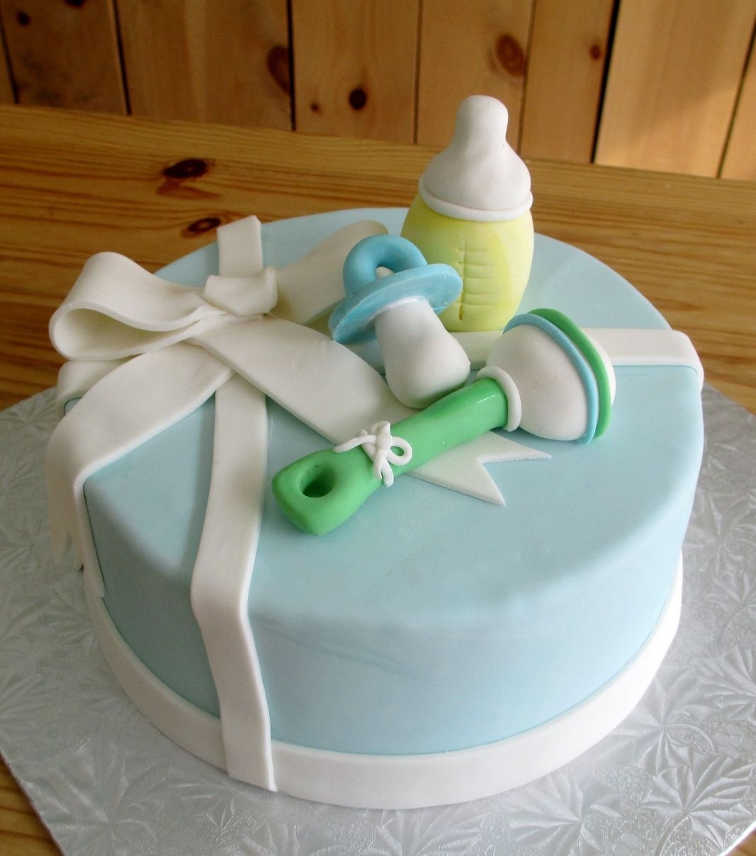 Gâteau shower de bébé garçon: gâteau avec une couverture au fondant et décoré d'items de bébé: suce, hochet et biberon.
