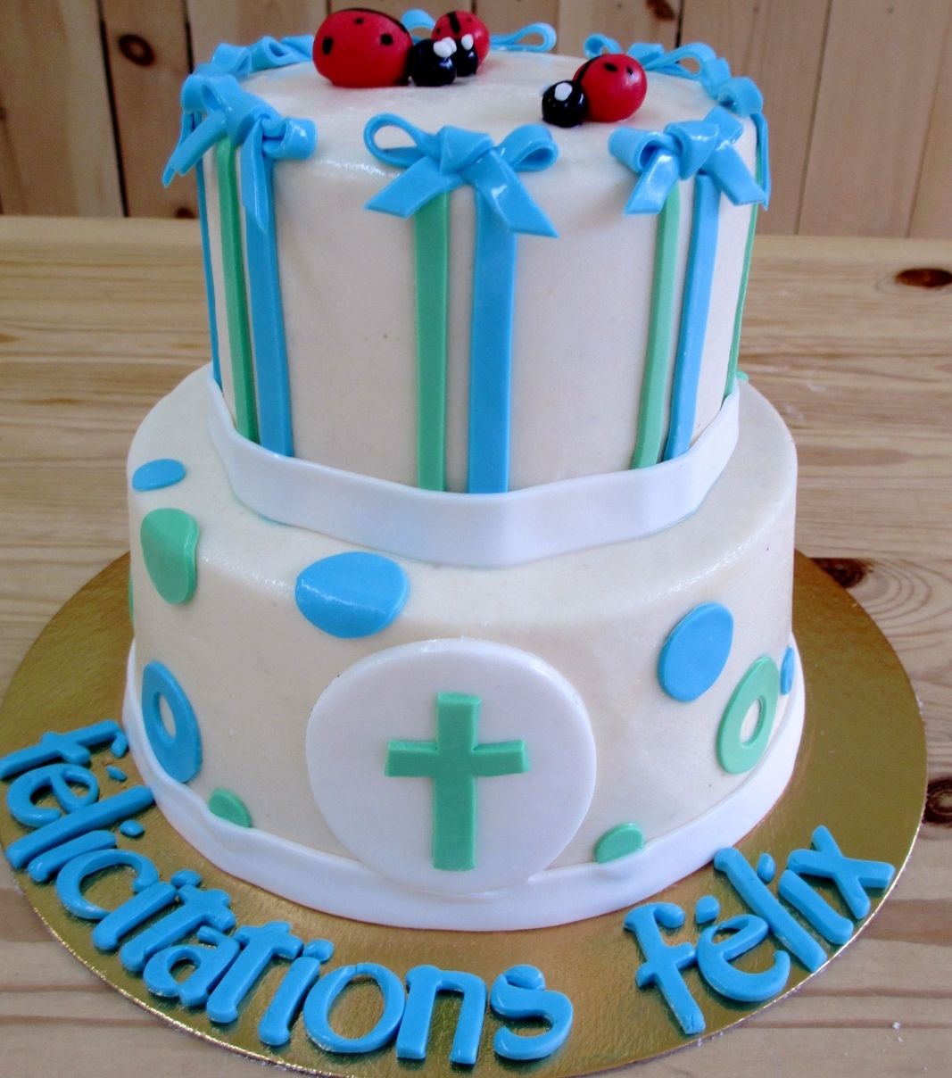 Gâteau de baptême de Félix: gâteau de 2 étages à thématique de coccinelle avec une couverture en pâte d'amande naturelle bleue et verte et décoré d'une croix verte.