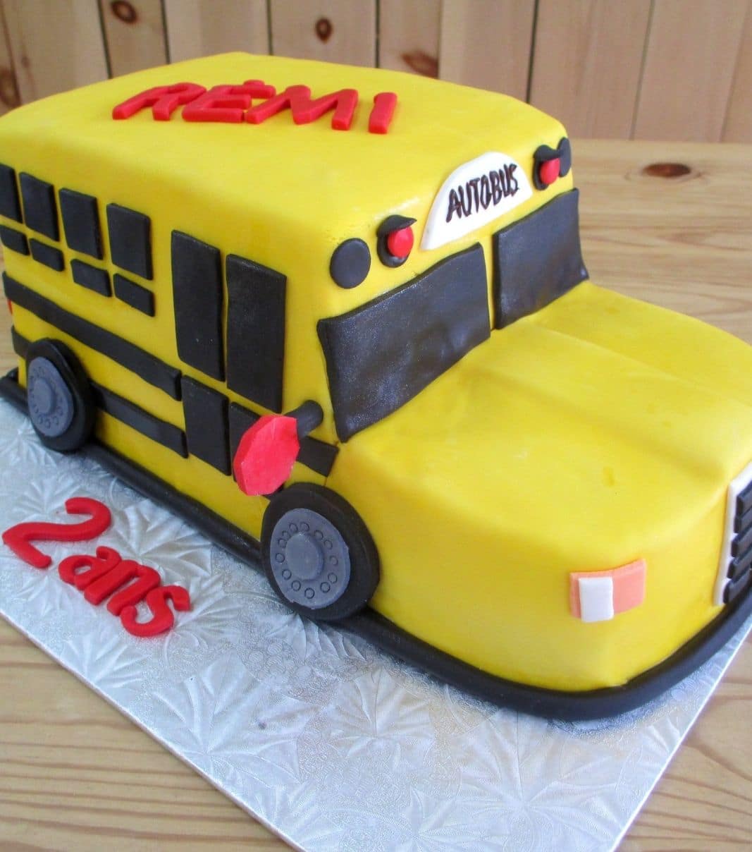 Gâteau d'anniversaire sur mesure des 2 ans de Rémi: gâteau 3D à thématique d'autobus scolaire jaune avec une couverture en fondant.