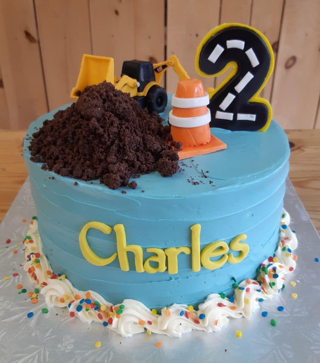 Gâteau d'anniversaire sur mesure des 2 ans de Charles: gâteau à thématique construction avec une couverture à la crème au beurre et décoré d'un cône de construction en fondant, d'un tracteur en plastique et de terre en brownie au chocolat.
