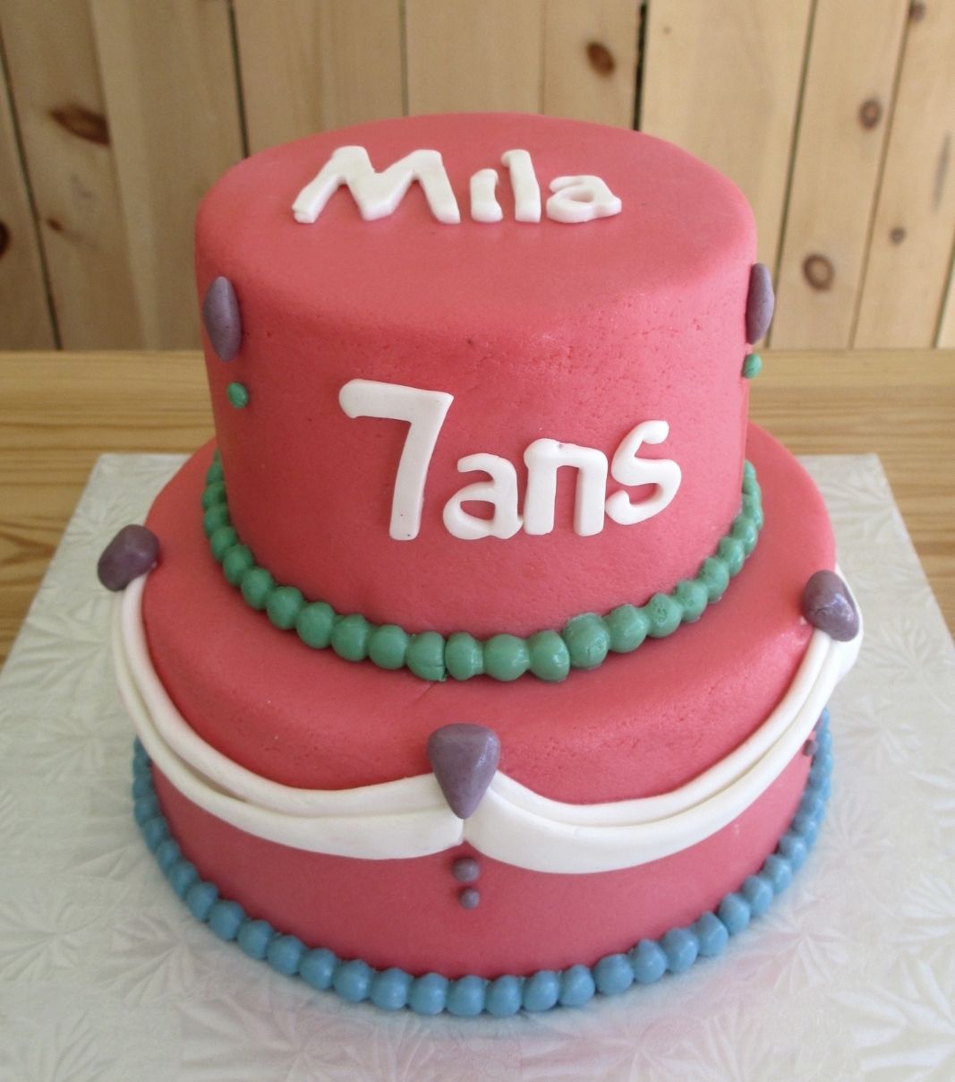 Gâteau d'anniversaire sur mesure des 7 ans de Mila: gâteau de 2 étages à thématique de princesse avec une couverture en pâte d'amande rose et ornementé d'un drapé blanc.