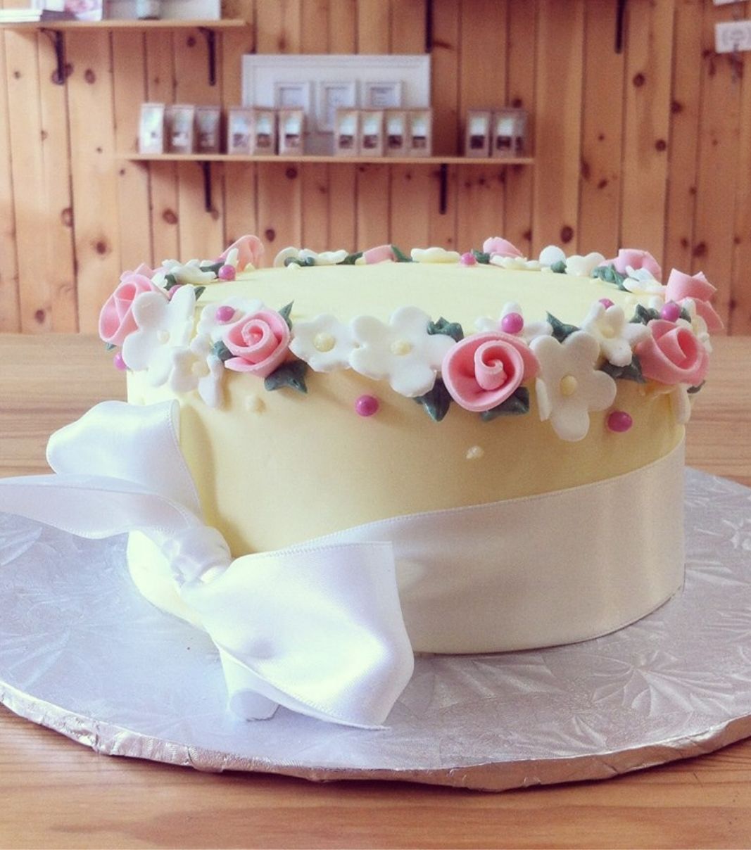 Gâteau d'anniversaire sur mesure: gâteau féminin avec une couverture en fondant jaune pastel et une bordure de fleurs en fondant.