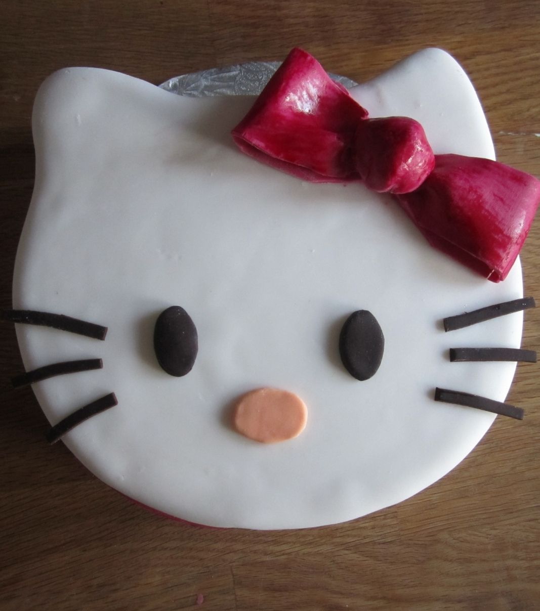 Gâteau d'anniversaire sur mesure: gâteau à thématique Hello Kitty avec une couverture en fondant blanc.