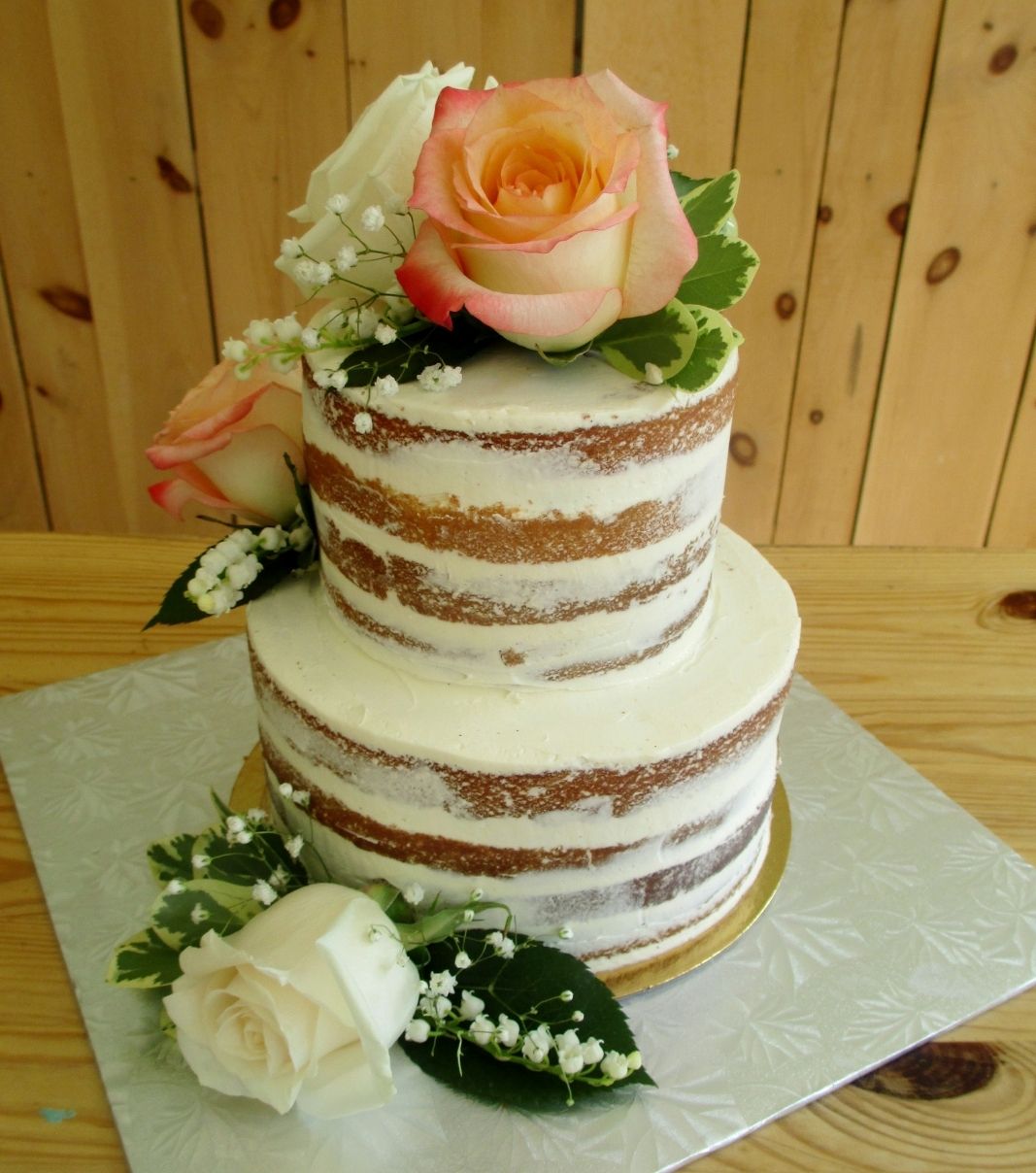 Gâteau d'anniversaire sur mesure: gâteau de 2 étages effet nu sali (naked) et décoré de roses fraîches, de soupir de bébé frais et de fleurs fraîches.
