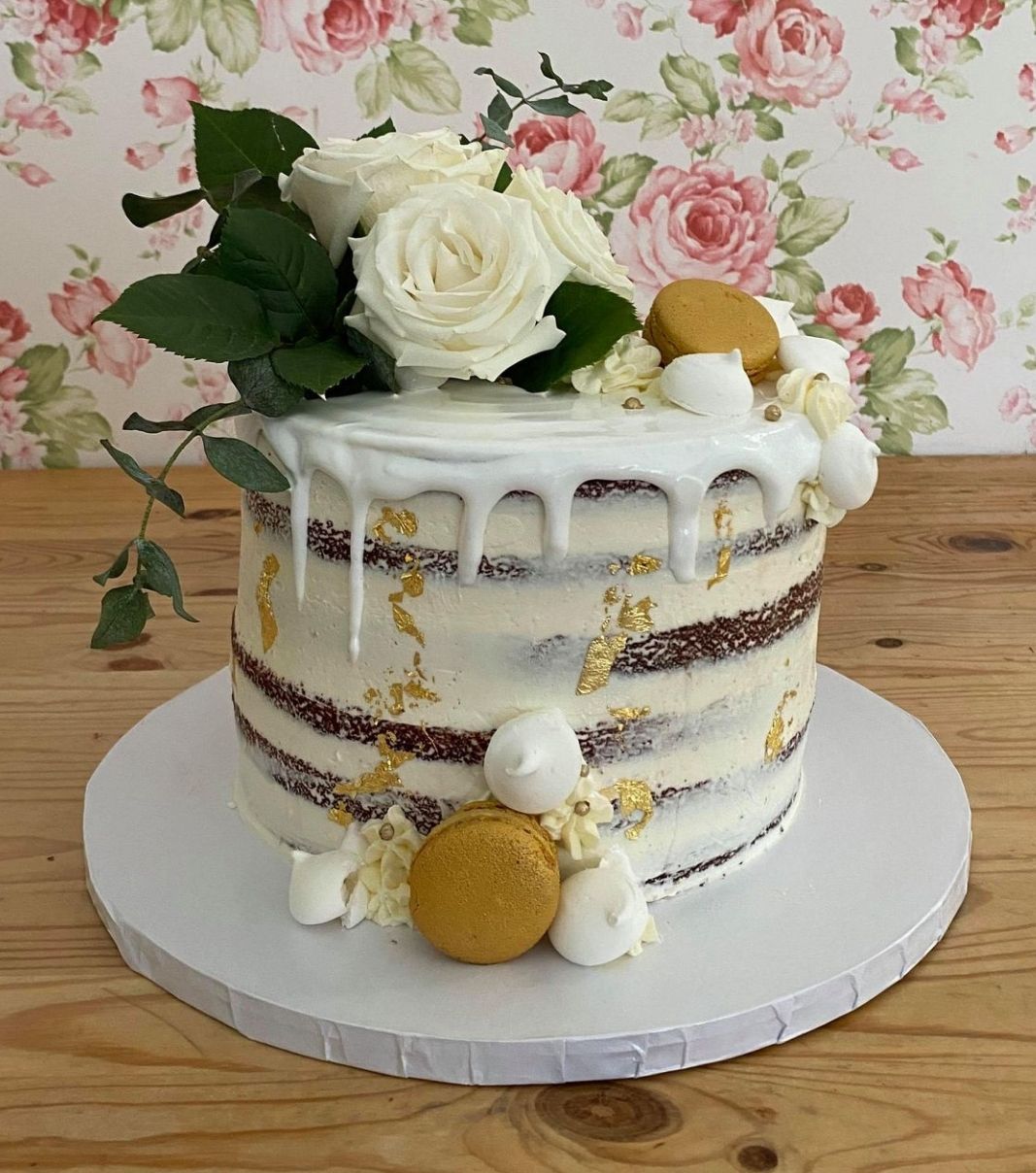 Gâteau d'anniversaire sur mesure: gâteau effet nu sali (naked) avec un coulis blanc et décoré de feuilles d'or et de fleurs fraîches.
