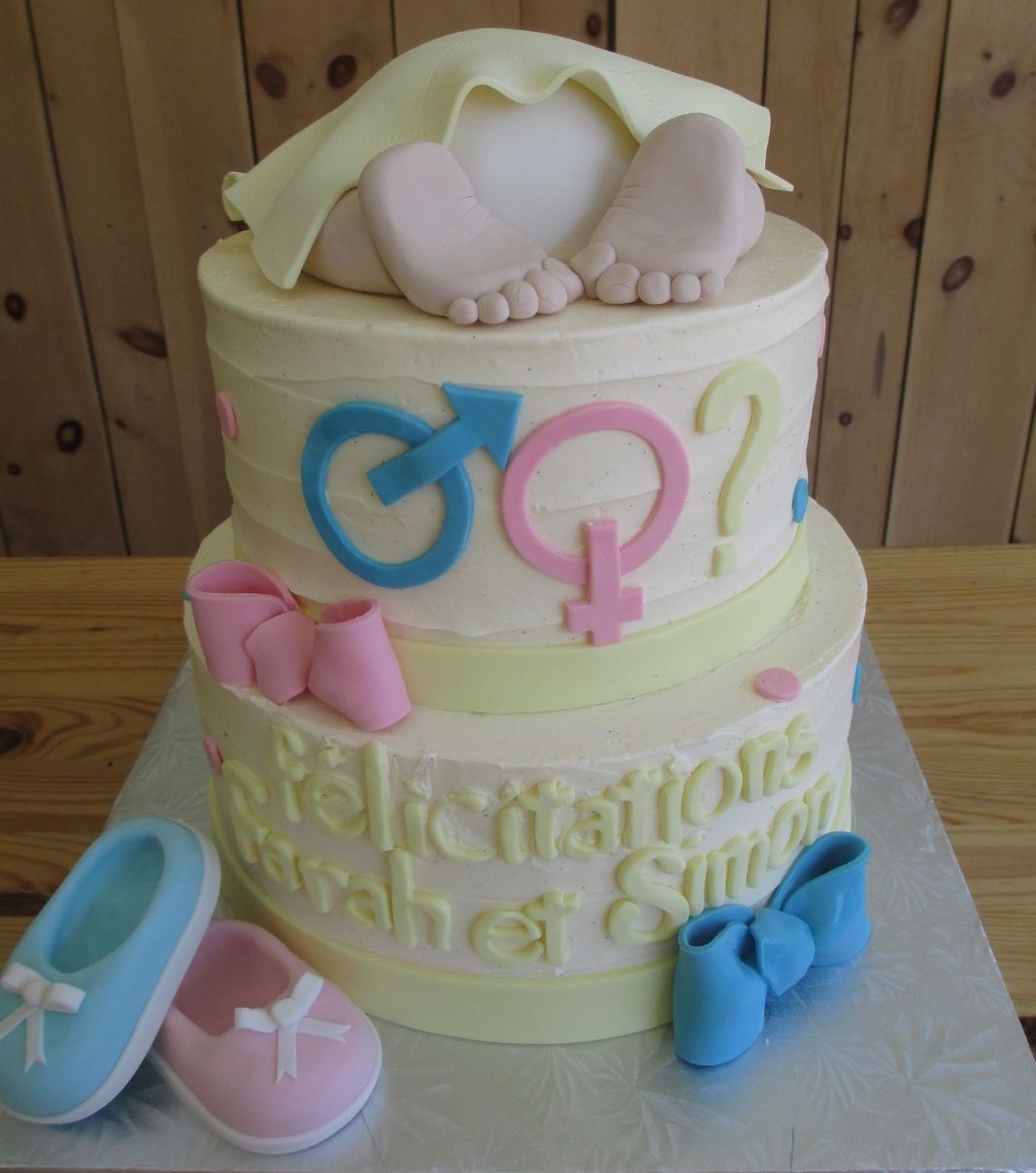 Gâteau "gender reveal" pour Farrah et Simon: gâteau de 2 étages avec des chaussons, un petit popotin de bébé et une couverture à la crème au beurre.