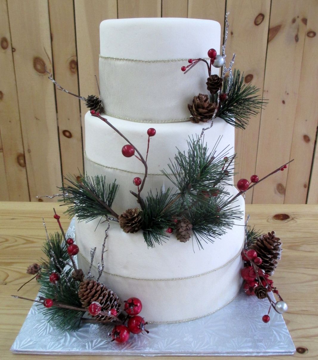 Gâteau de mariage: gâteau de 3 étages à thématique hivernale avec une couverture au fondant blanc et décoré de cocottes, de sapinage et de rubans en tissu.