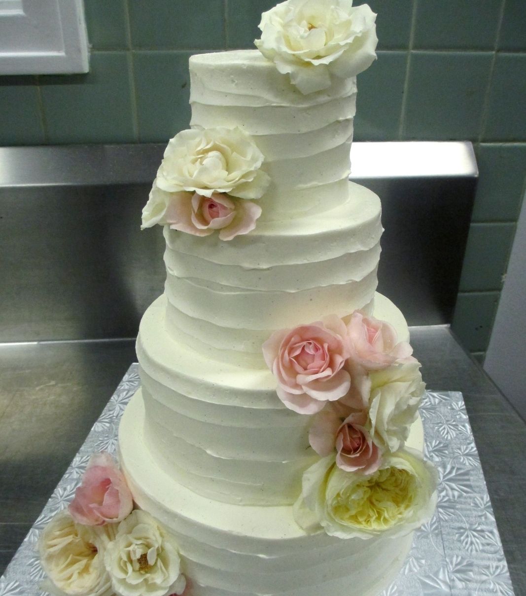 Gâteau de mariage: gâteau de 4 étages avec une couverture effet de coup de spatule et décoré de fleurs fraîches, de pivoines et de roses.