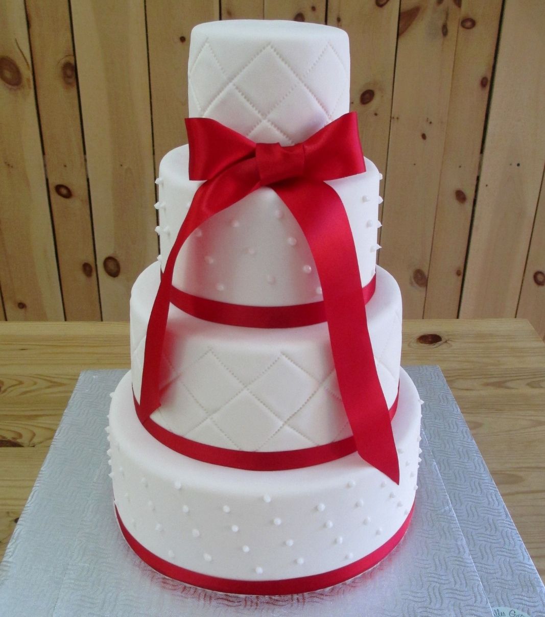 Gâteau de mariage: gâteau de 4 étages avec une couverture au fondant blanc et décoré de rubans de tissu rouge.