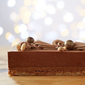 Photo du gâteau Royal choco-arachide: Mousse au chocolat noir sur biscuit dacquoise et croustillant à l'arachide garni de chantilly au chocolat au lait, boules maltées enrobées de poudre dorée comestibles et céréales croustillantes au chocolait noir