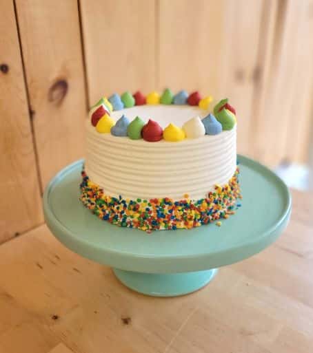 Découvrez notre gâteau d'anniversaire funfetti avec crème au beurre coloré et bordure de bonbons multicolores