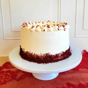 Découvrez notre gâteau rouge velours de 12 parts. Il est masqué de crème au beurre blanche et a une bordure de poudre de gâteau rouge velours à sa base.