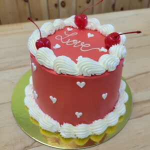 SPÉCIAL ST-VALENTIN : Gâteau chocolat garni de mousse biscuits et crème et ganache chocolat noir, masqué de crème au beurre rose et petits coeurs.