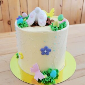 Gâteau au chocolat garni de crème légère à la vanille et de cocos de Pâques masqué de crème au beurre à la vanille avec un popotin de lapin.