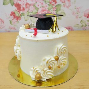 Gâteau anniversaire thématique pour une graduation. Gâteau au chocolat, mousse vanille avec décor de crème au beurre, mortier, diplôme et perles dorées.