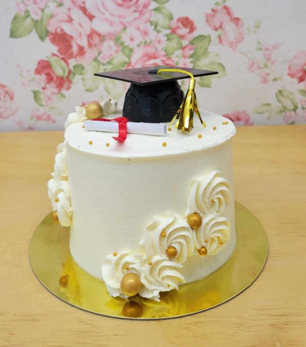 Gâteau anniversaire thématique pour une graduation. Gâteau au chocolat, mousse vanille avec décor de crème au beurre, mortier, diplôme et perles dorées.